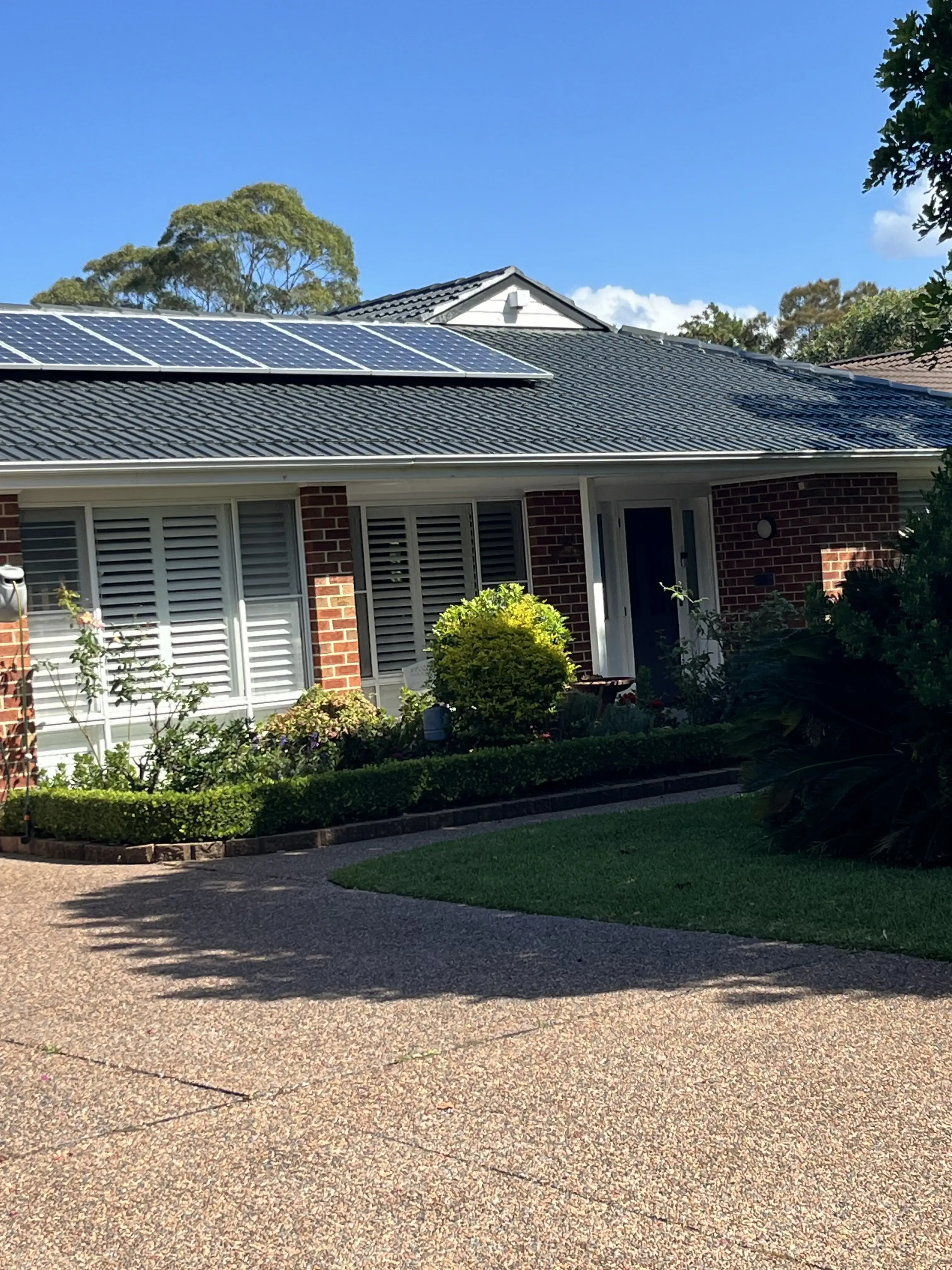 A house with solar panels on the roof and a driveway — Norwest Roof Restorations In Central Coast, NSW