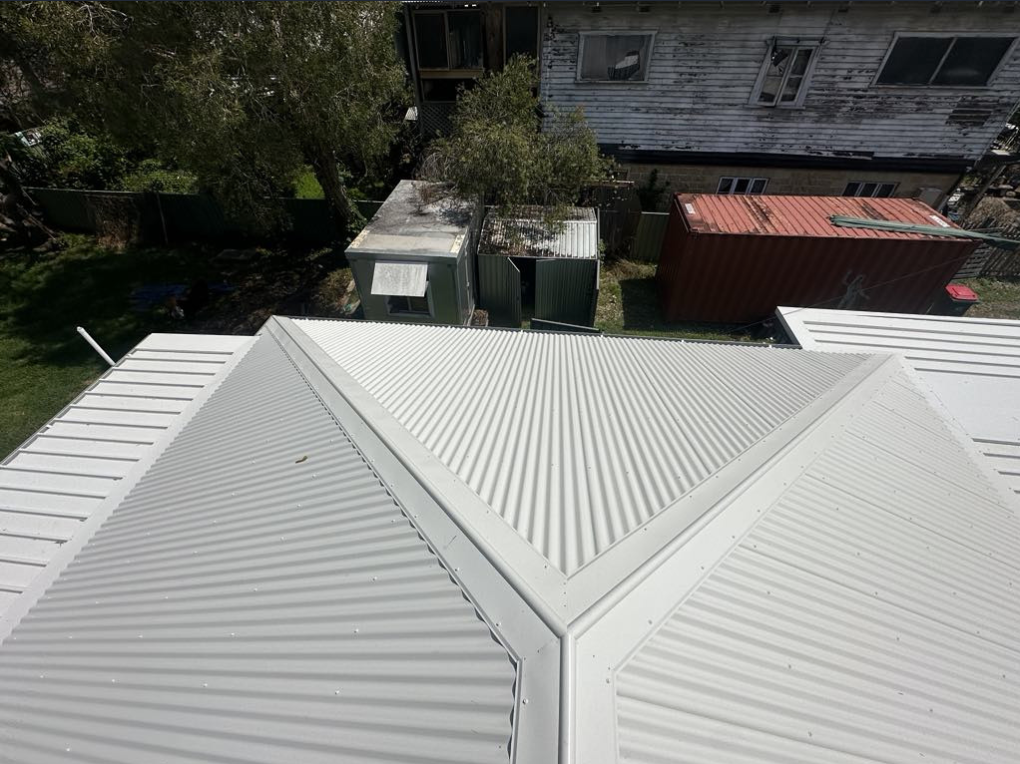 A Person Wearing Yellow Gloves is Working on a Roof — Norwest Roof Restorations In Central Coast, NSW