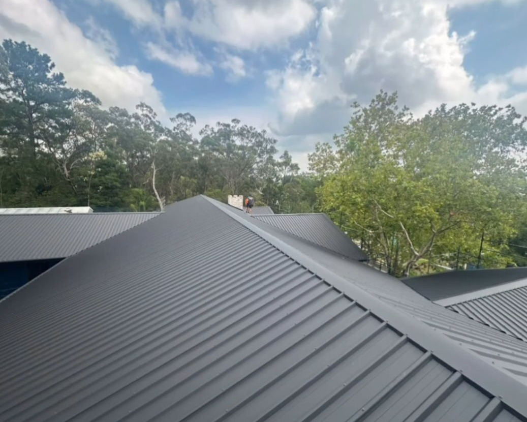 Metal Roof With Ridges Under a Cloudy Sky — Norwest Roof Restorations In Lake Macquarie, NSW