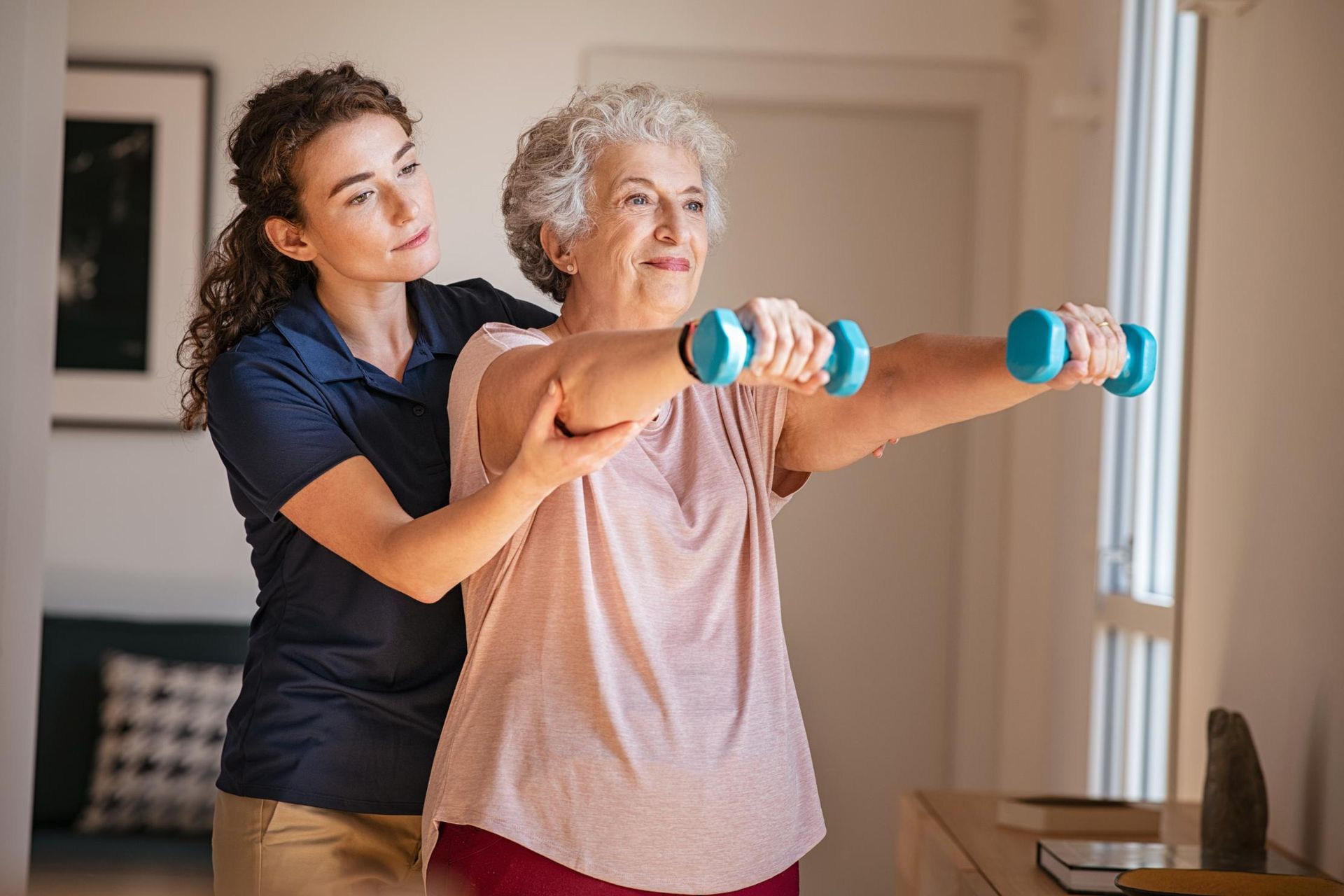 Woman with a trainer doing arm exercises with small weights.