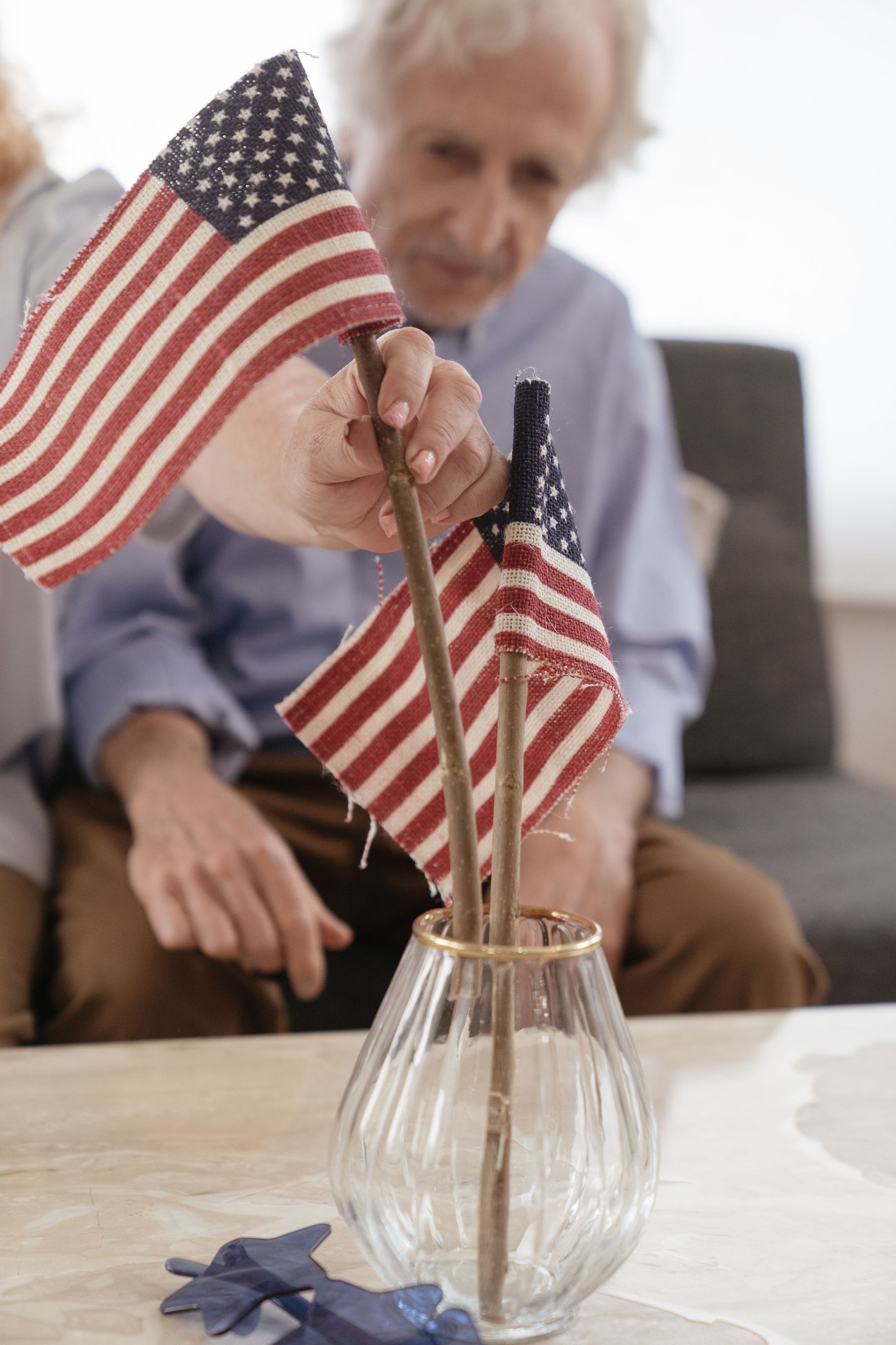 Person placing small American flags in a vase on a table