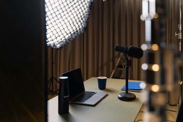 Podcast recording setup with microphone, laptop, and light.