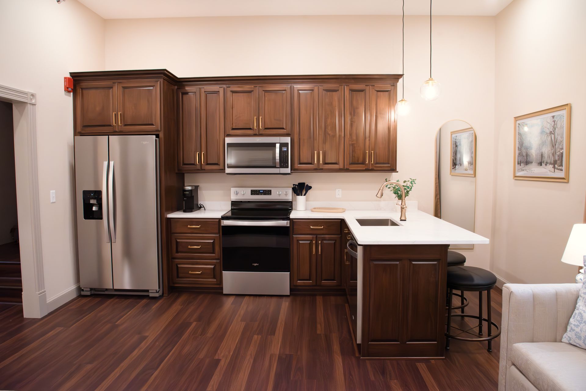 Kitchen with dark wood cabinets, stainless steel appliances, white countertops, and a small breakfast bar.
