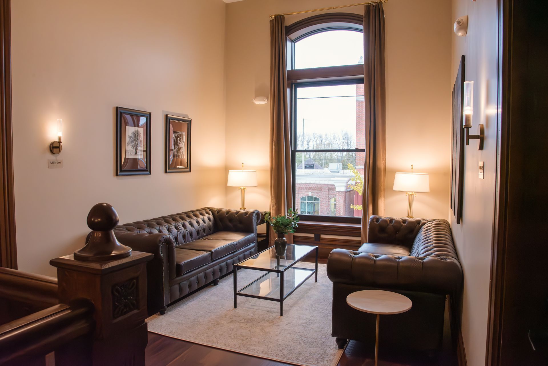 Living room with brown leather sofas, coffee table, and tall window.
