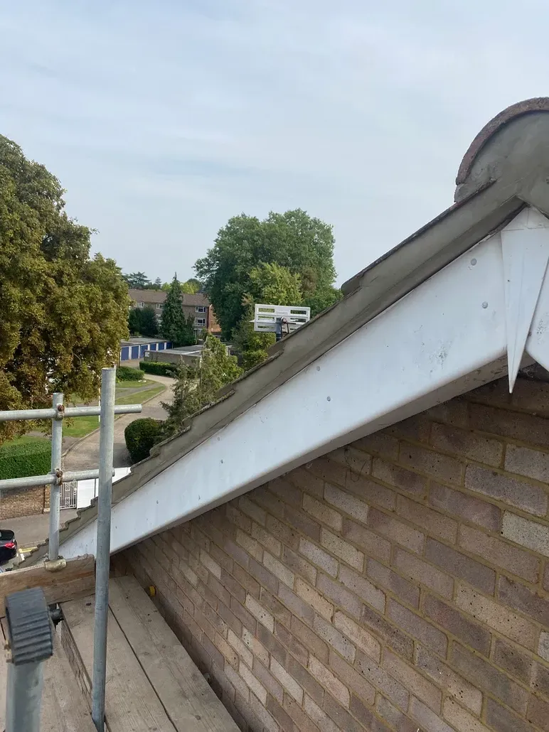 A brick building with a white trim facia and soffit on the roof.