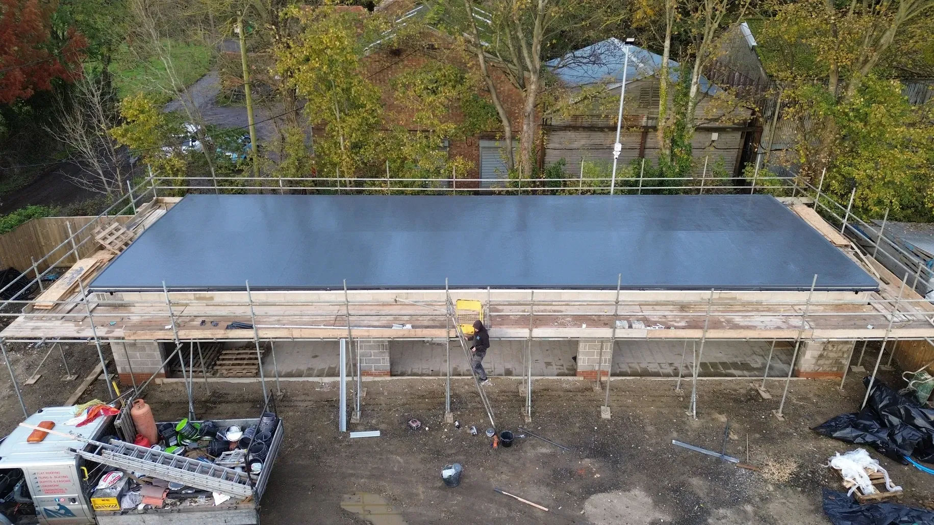 An aerial view of a building under construction with scaffolding and a truck.