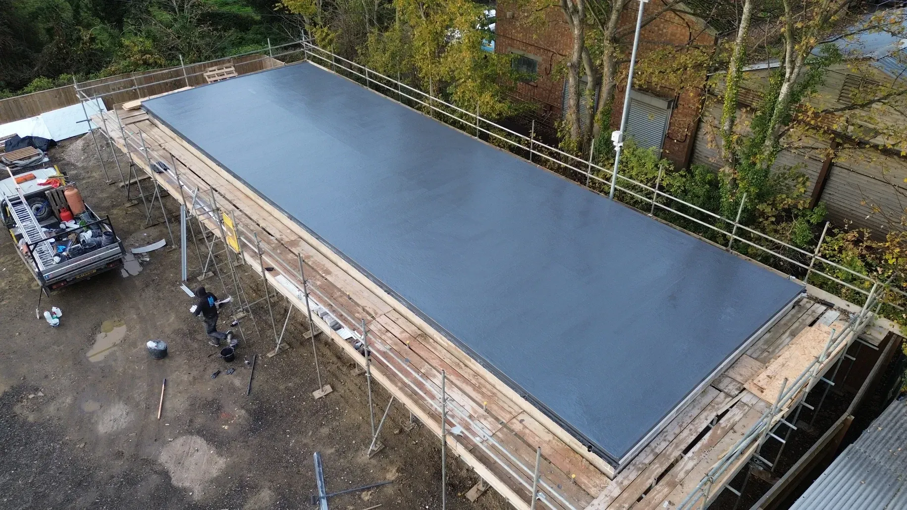 An aerial view of a large black roof under construction.