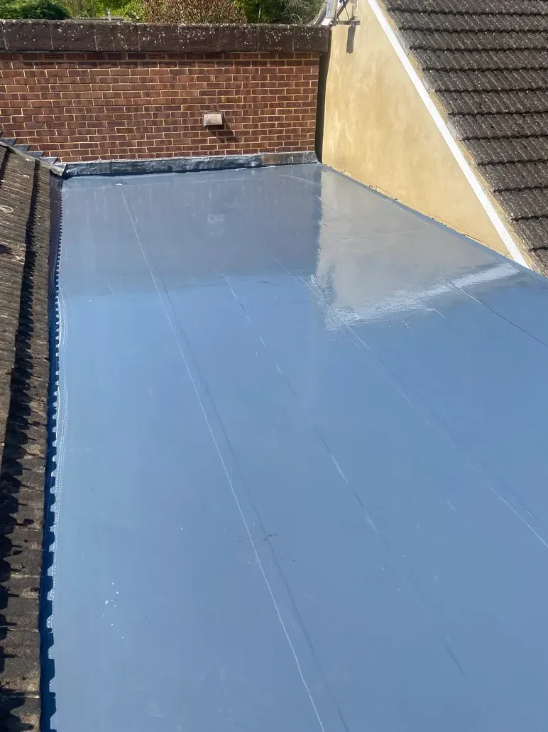A close up of a roof with a brick wall in the background.