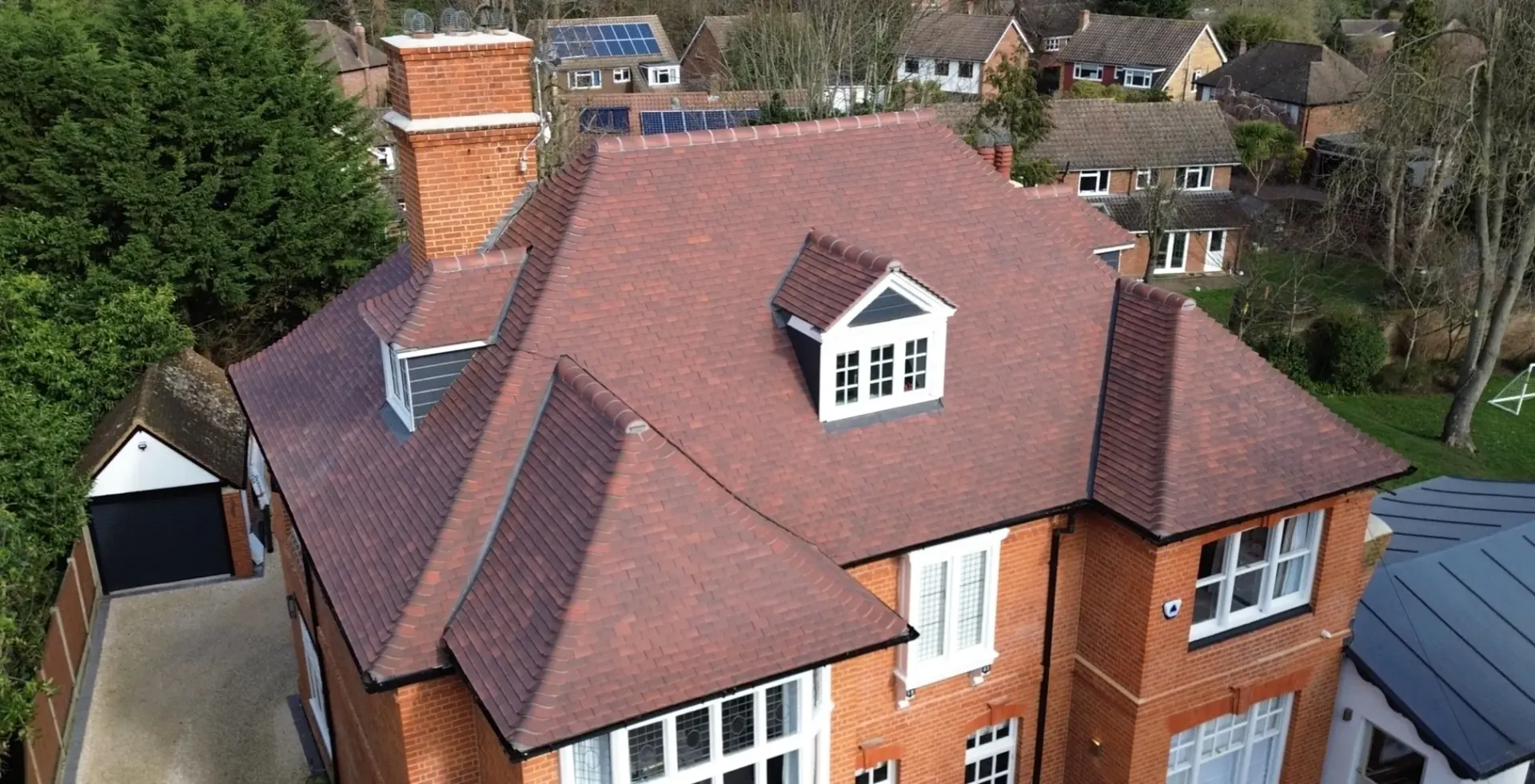 An aerial view of a large brick house with tiled roof.