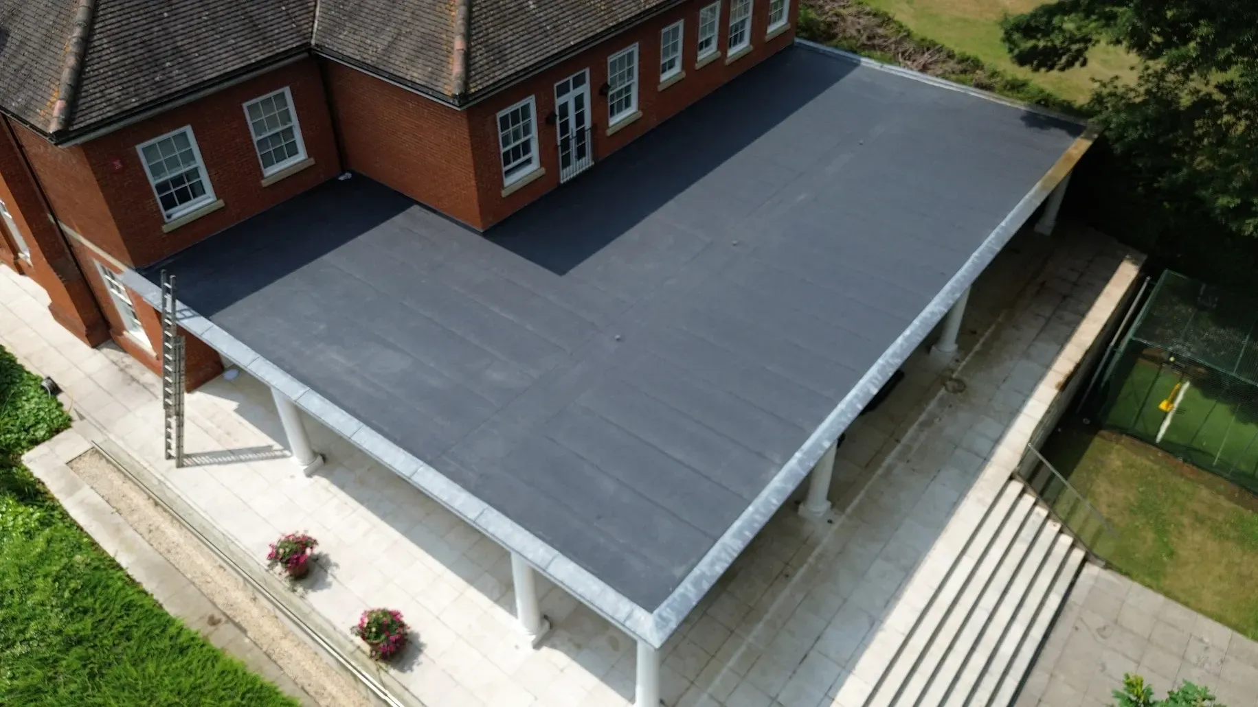 An aerial view of a large brick building with a black flat roof.