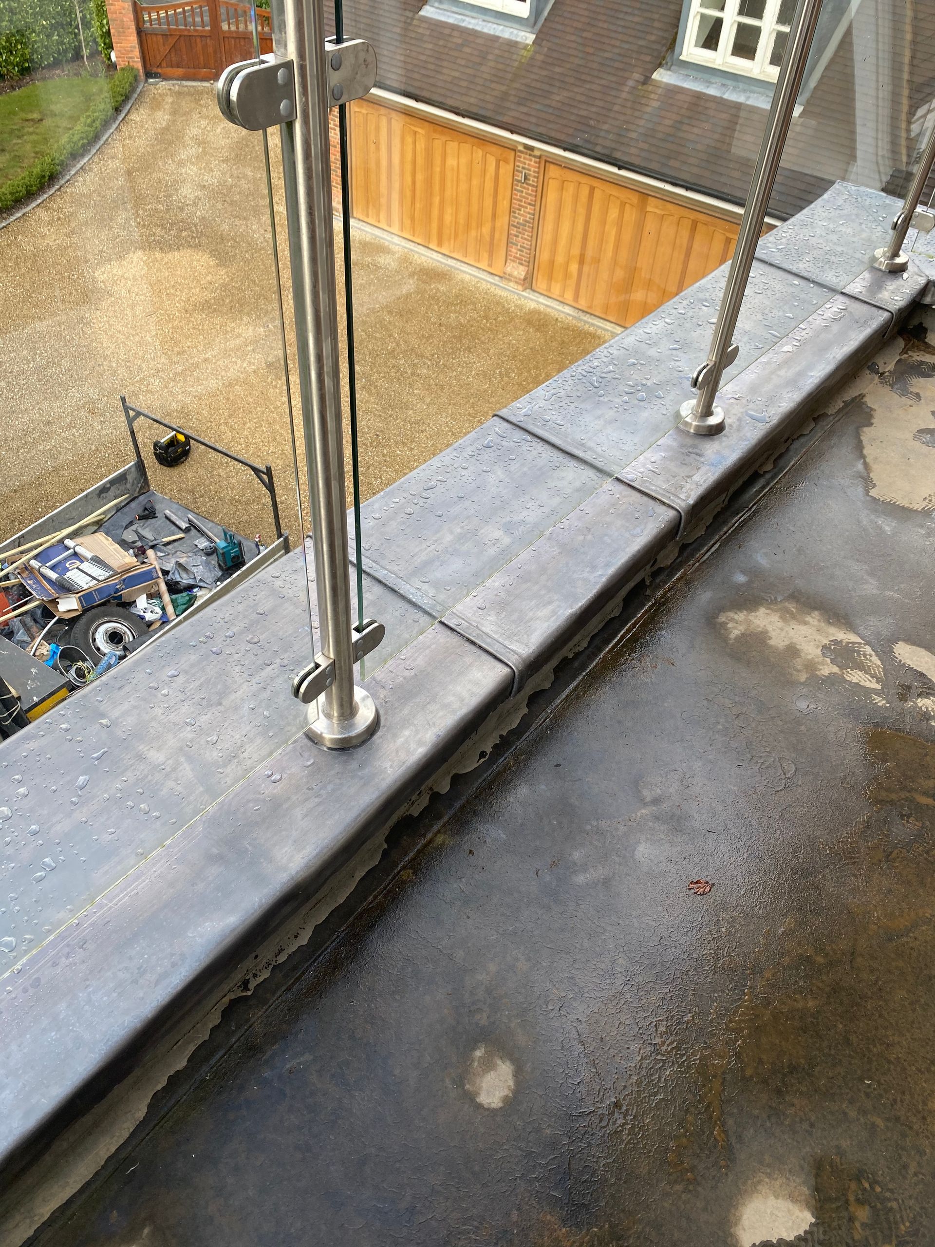 a balcony with a stainless steel railing and a wooden garage in the background .