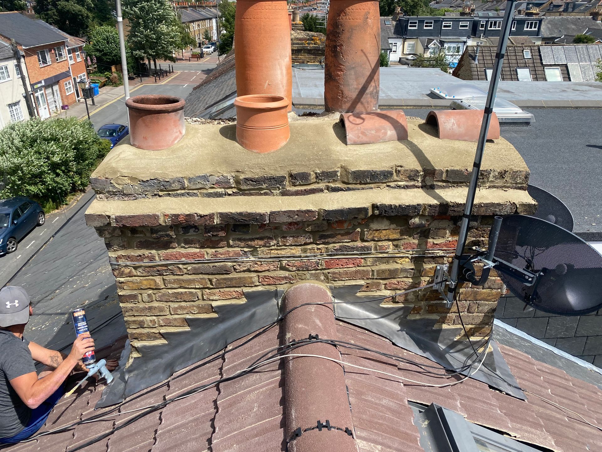 a man is working on a chimney on the roof of a building .