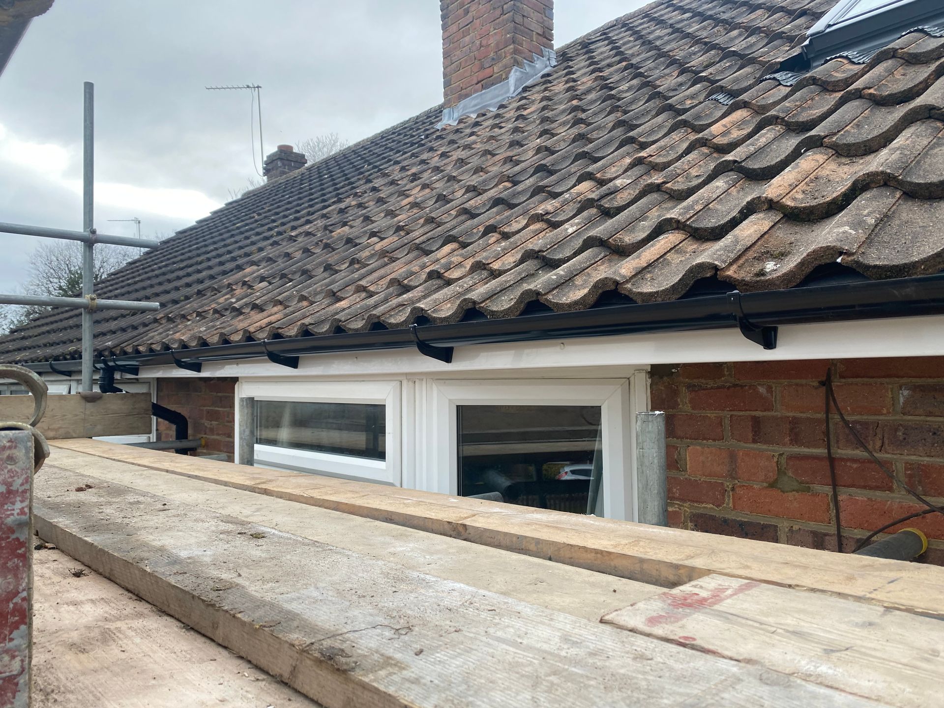 a brick house with a tiled roof and a wooden scaffolding in front of it .