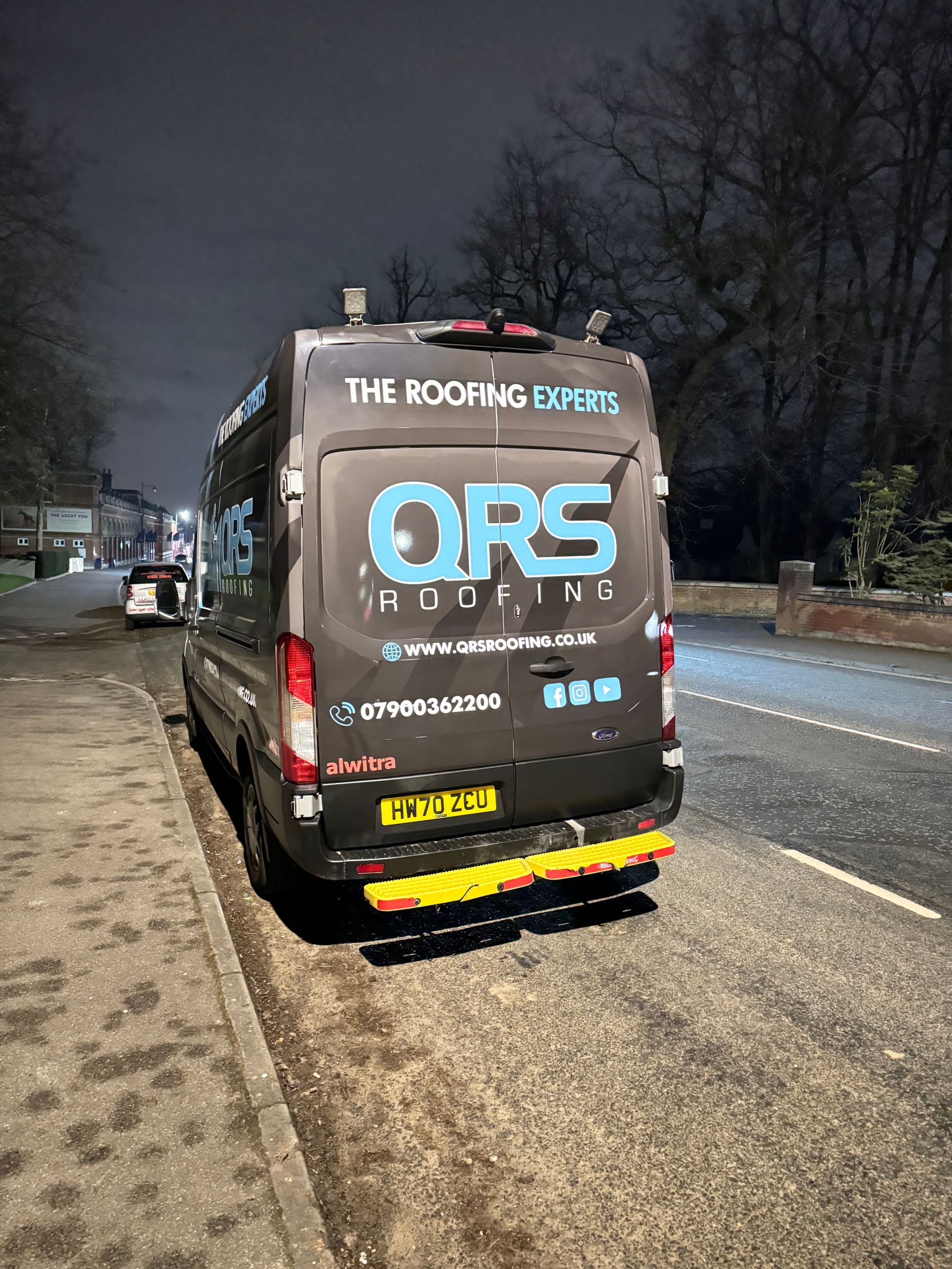A black van is parked on the side of the road at night.