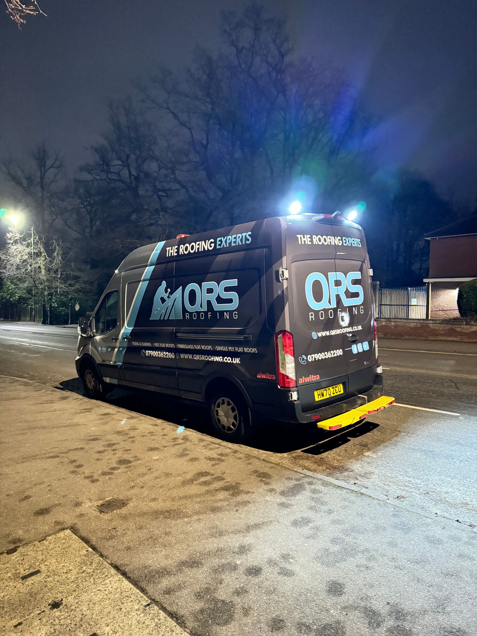 A black van is parked on the side of the road at night.