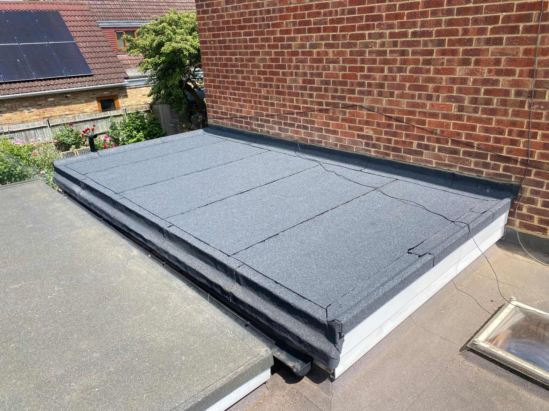 a gray felt roof with a brick wall in the background .