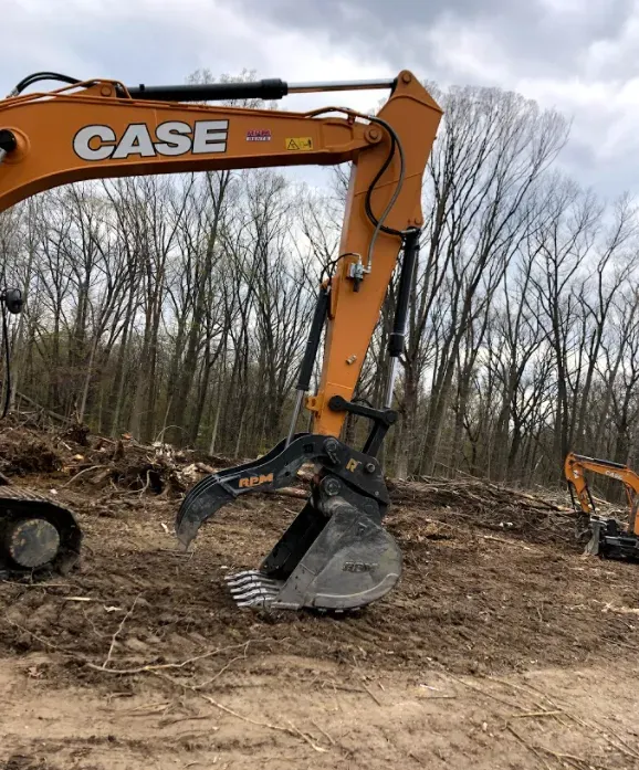 Orange Case excavator with a grapple bucket in a clearing, trees in background.