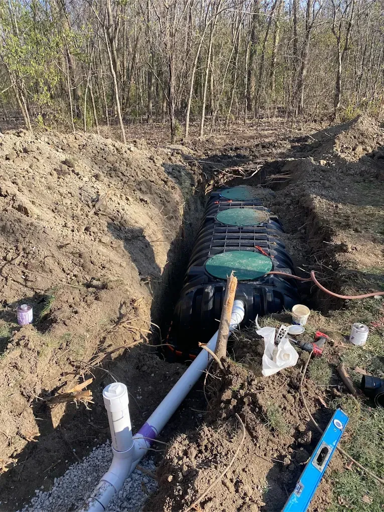 A septic tank installation in a trench, with PVC pipes and a level.
