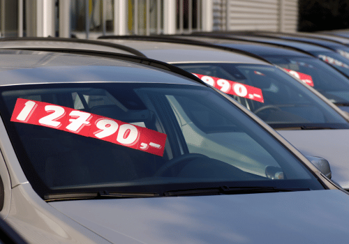 Cars on a lot with red price tags displayed on windshields