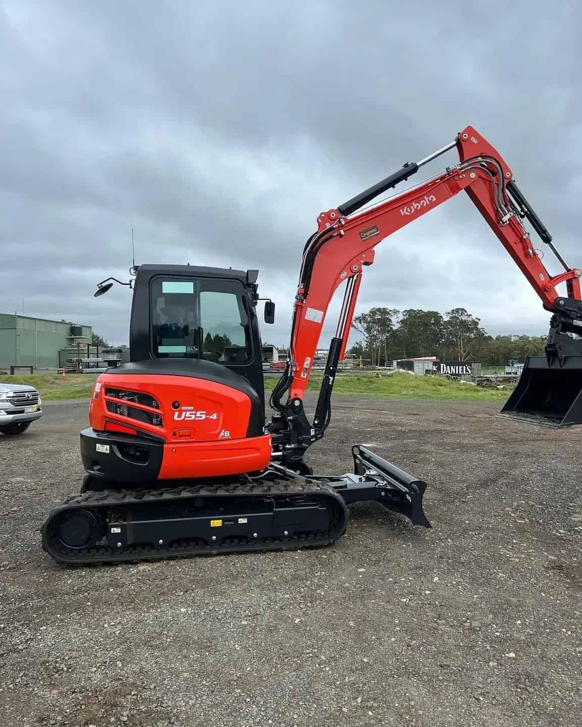 A Red And Black Excavator Is Parked In A Gravel Lot — Tymmo's Tippers In Byron Bay, NSW