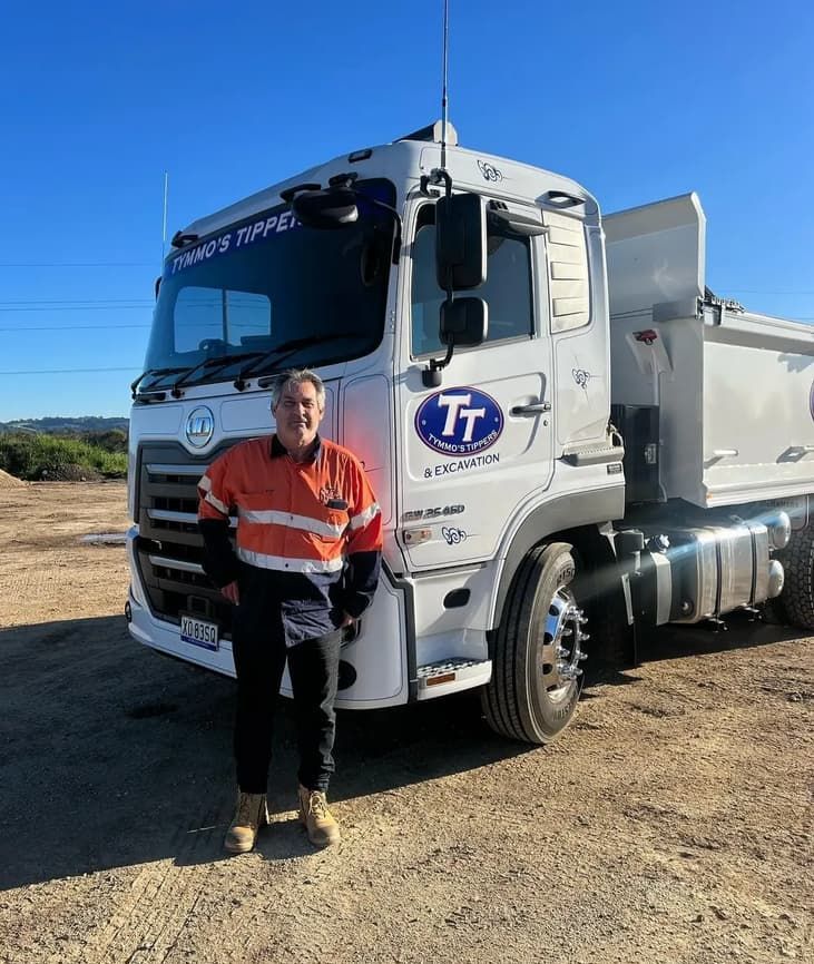 A Man Is Standing In Front Of A Dump Truck — Tymmo's Tippers In West Ballina, NSW
