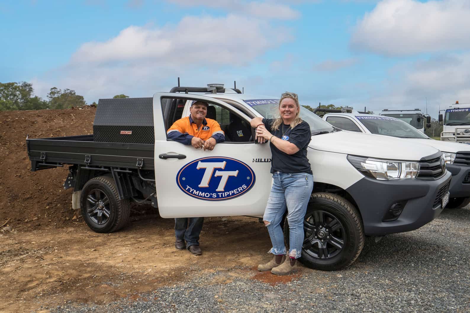 A Man And A Woman Are Standing Next To A Truck — Tymmo's In West Ballina, NSW