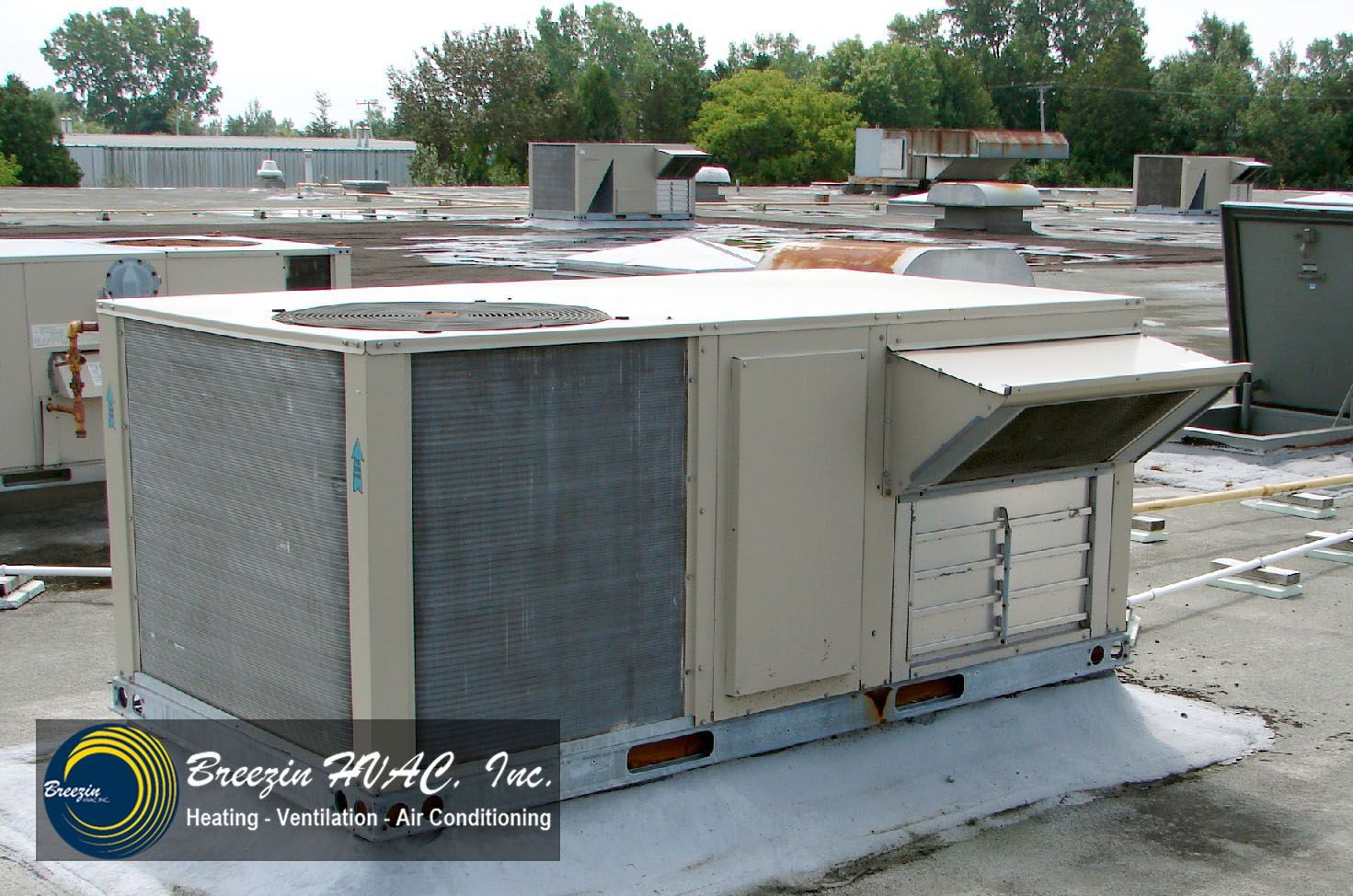 Large rooftop HVAC unit on a commercial building with ductwork and weathered metal panels.