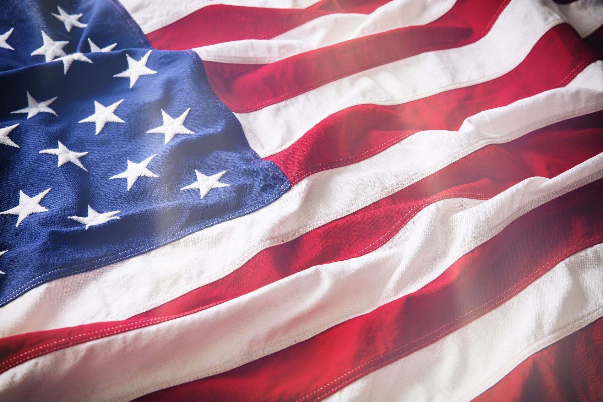 A close-up of a wavy, textured American flag with its blue canton and red and white stripes.