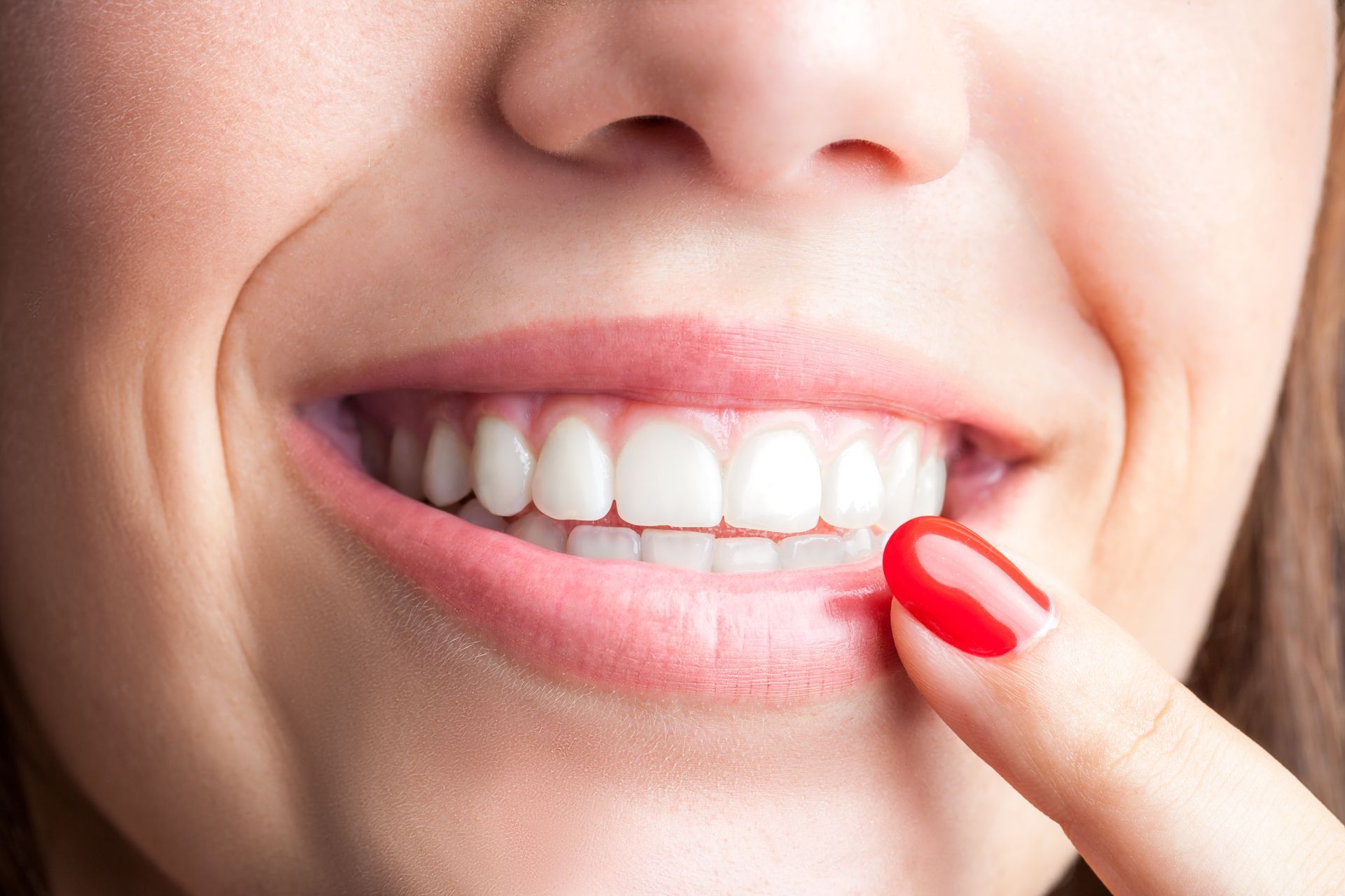Female finger pointing at teeth.