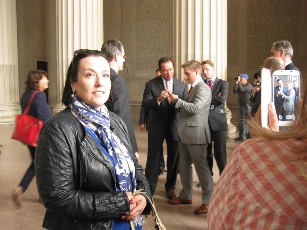 Donna standing at the Reflecting Pool in Washington DC, with Arnold Schwarzenegger photobombing her