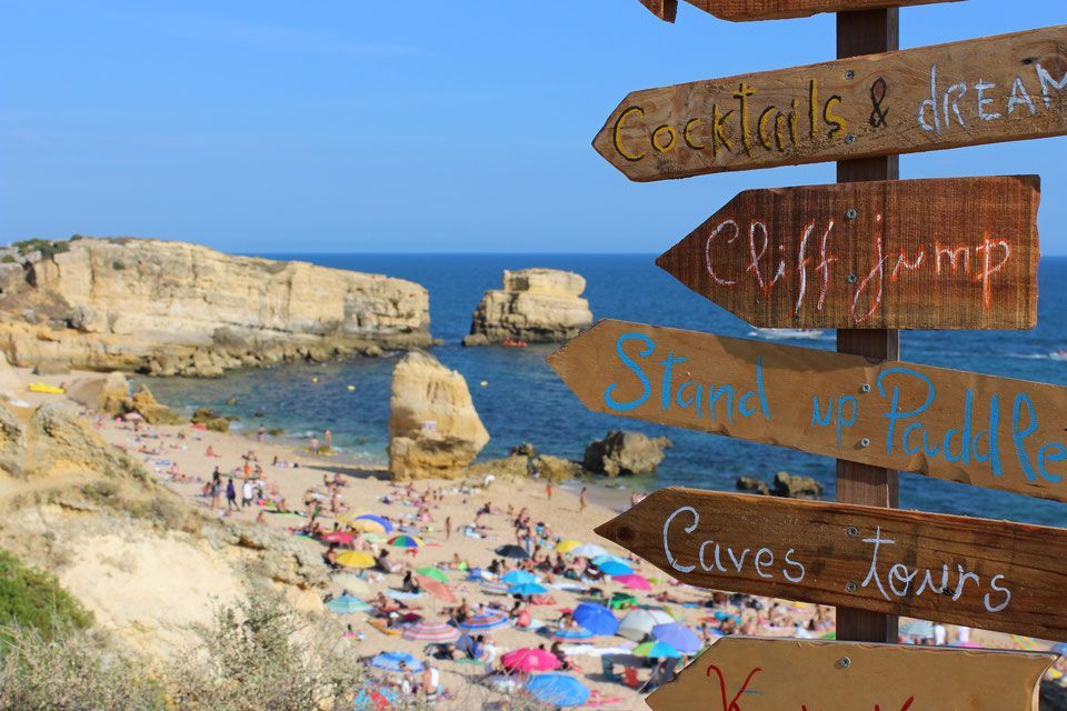 a beach with a sign pointing to cocktails and drinks