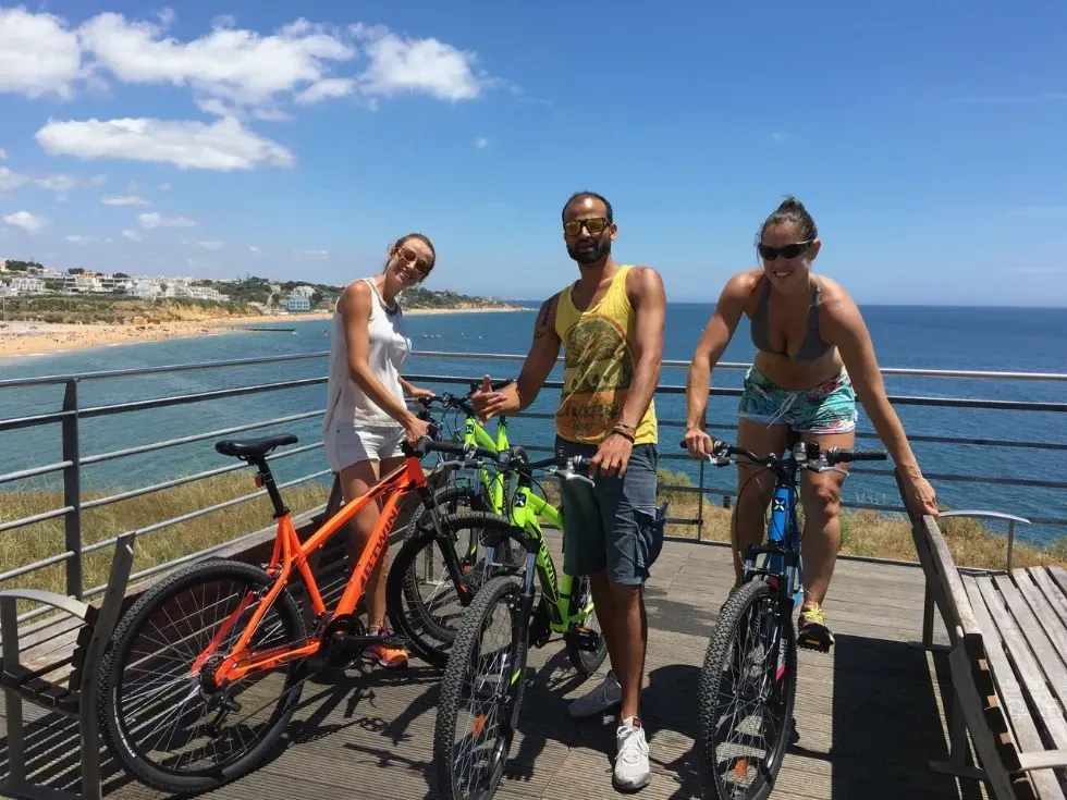 three people are standing next to bicycles on a balcony overlooking the ocean .