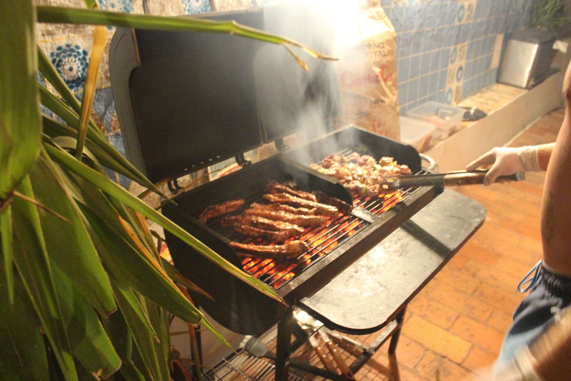 a person is cooking food on a grill outside Orange Terrace Hostel patio