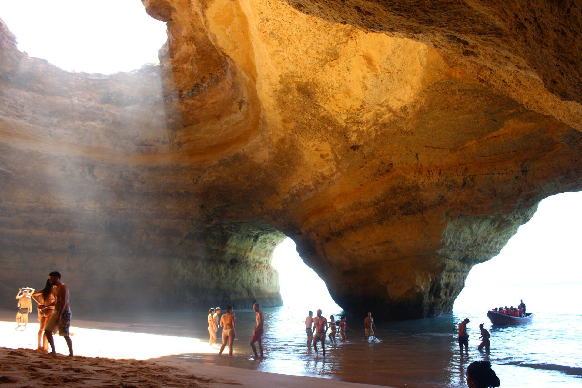 a group of people are standing in a Benagil Cave