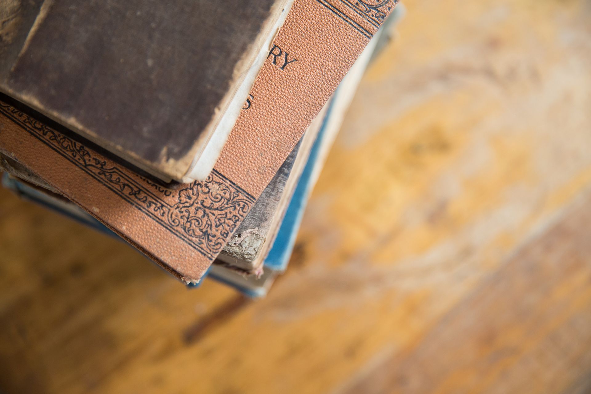 Stack of books on a wooden surface, with worn brown and blue covers.