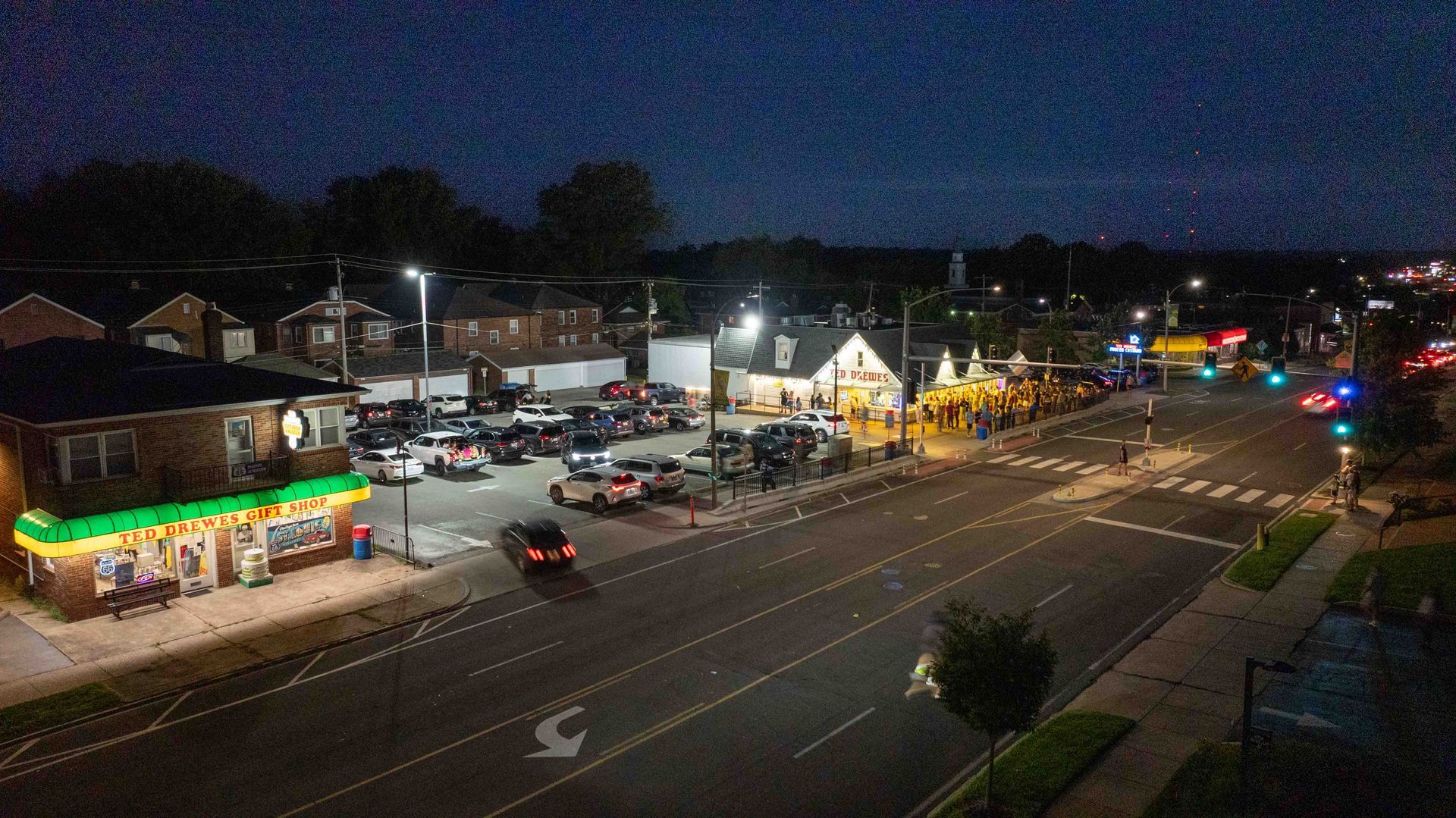 Nighttime photo showing Ted Drews with customers and neon lights