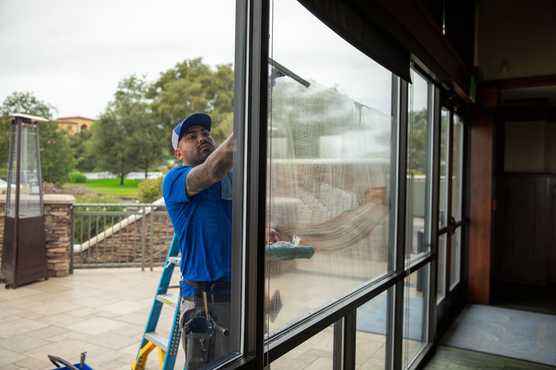 Worker cleaning a large window with a squeegee outside a modern building