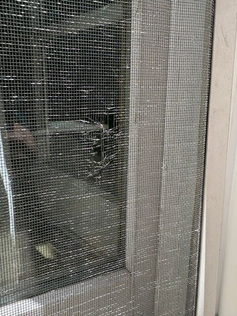 Close-up of a screen mesh being cut with a roller cutter on a white frame.