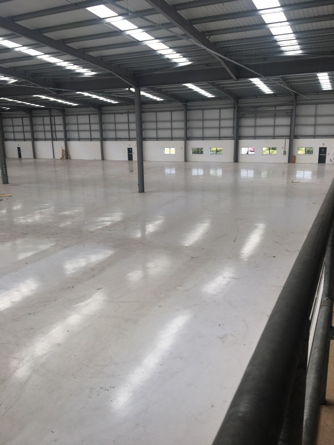 Empty industrial warehouse interior with polished concrete floor and skylights above