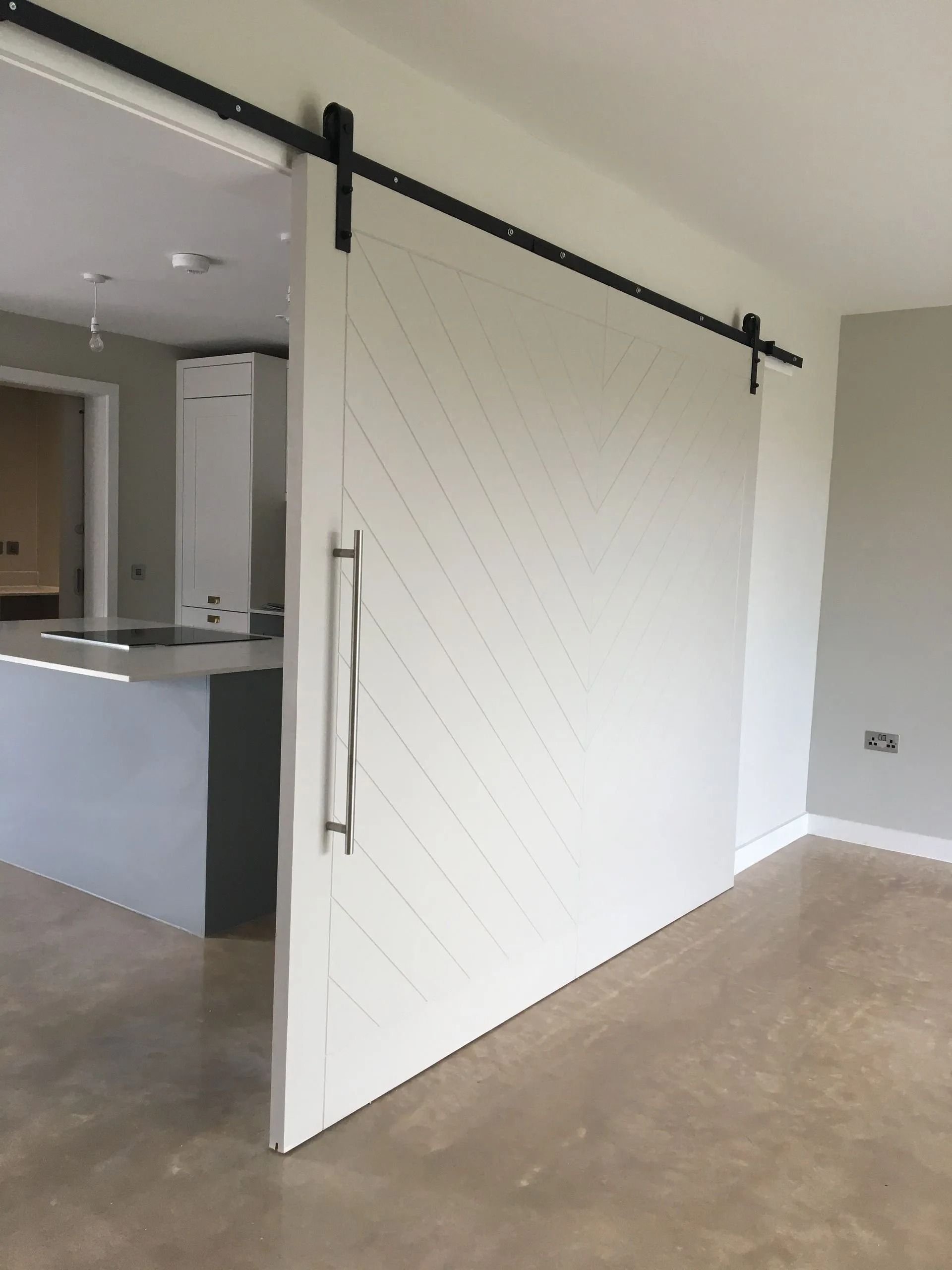 White barn-style sliding door on a track in a modern interior, partly open between kitchen and hallway