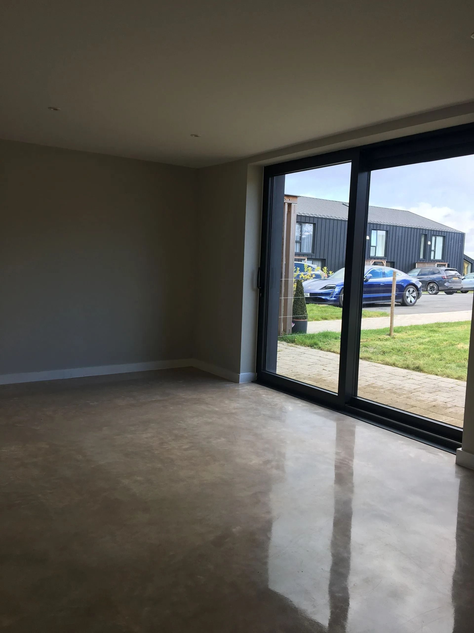 Empty living room with large sliding glass door opening to a suburban street view