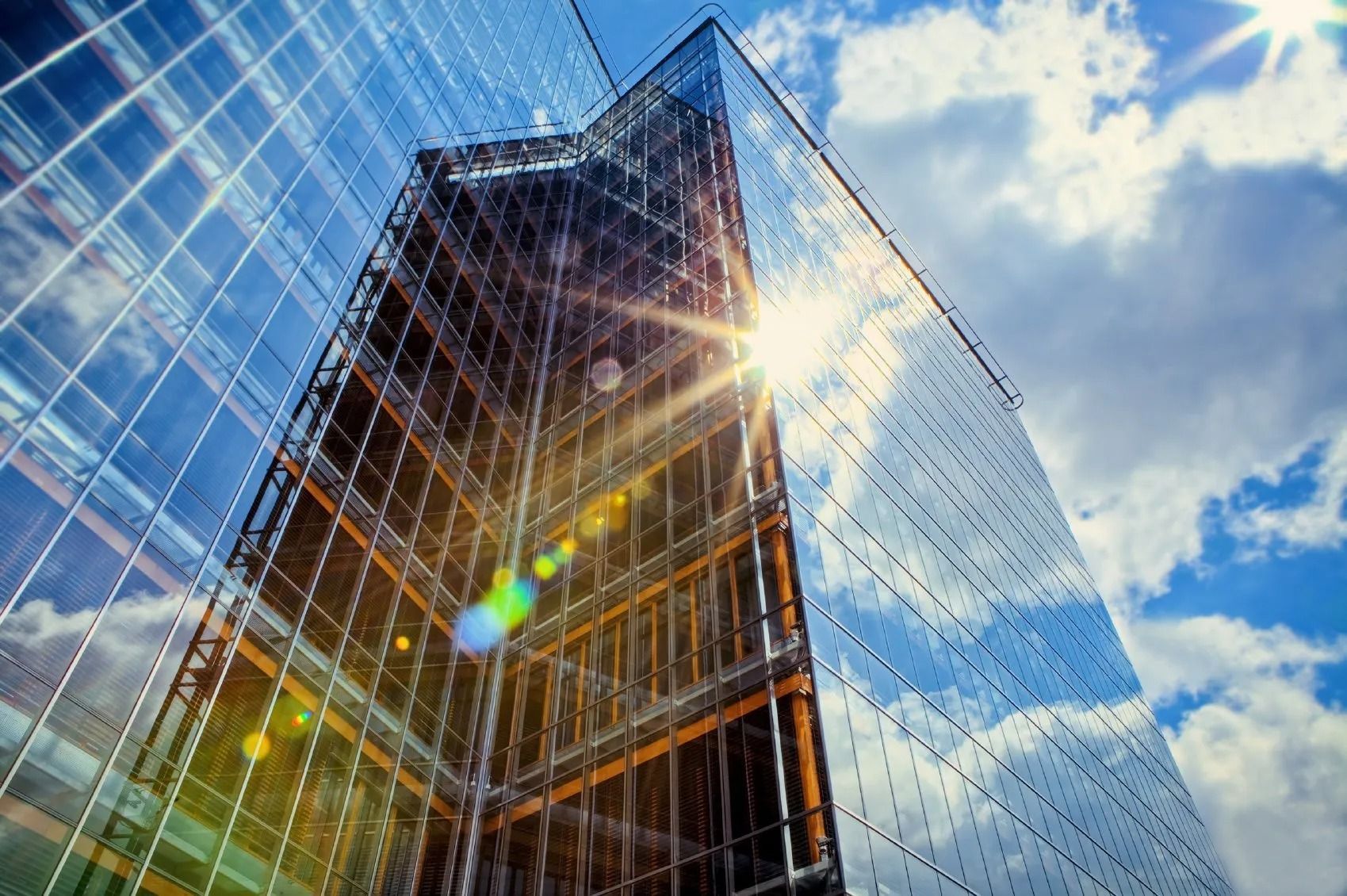 Glass office building reflecting a blue sky with sun flare