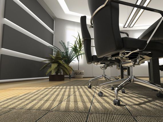 Modern office conference room with black chairs, patterned carpet, and a potted plant near the wall.