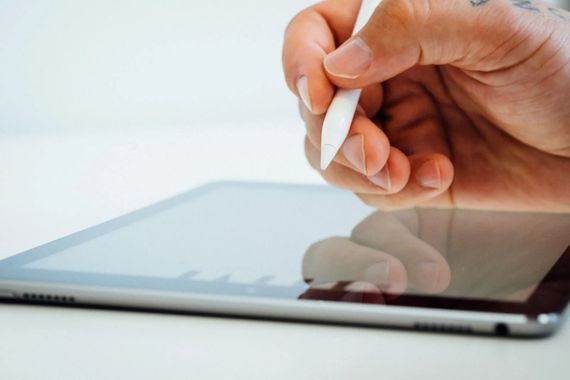 Hand using a stylus on a tablet screen