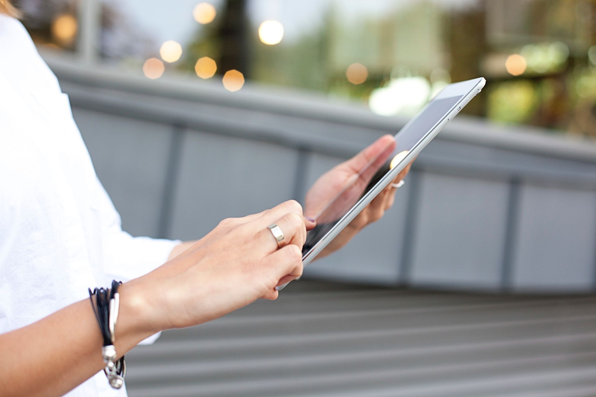 Person using a smartphone outdoors, with a blurred city background.