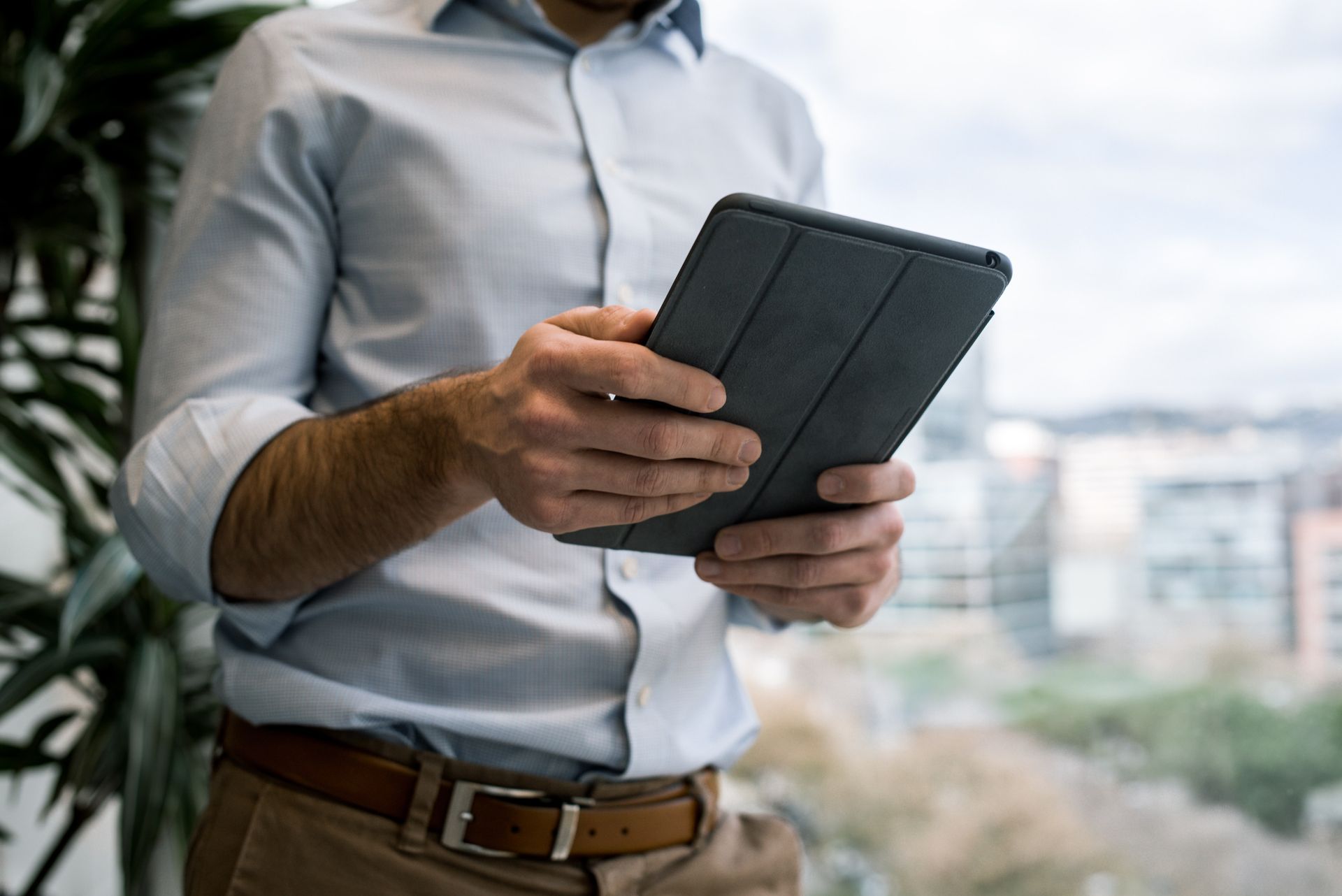 Person holding a tablet outdoors near an office building