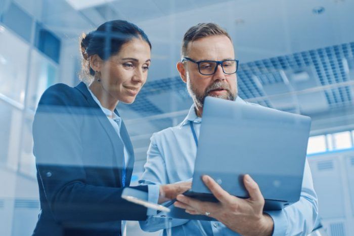 A man and a woman are looking at a laptop computer.
