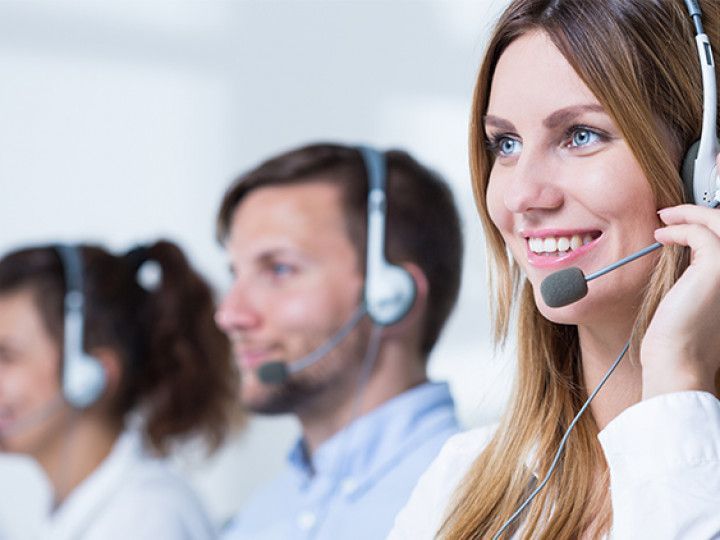 A group of people wearing headsets in a call center.