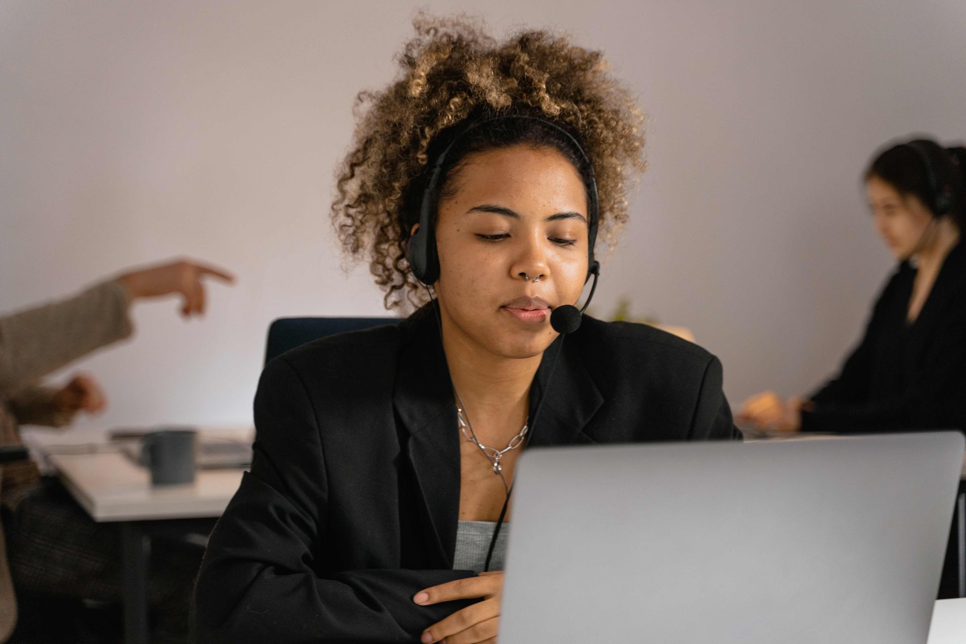 A woman wearing a headset is sitting in front of a laptop computer.