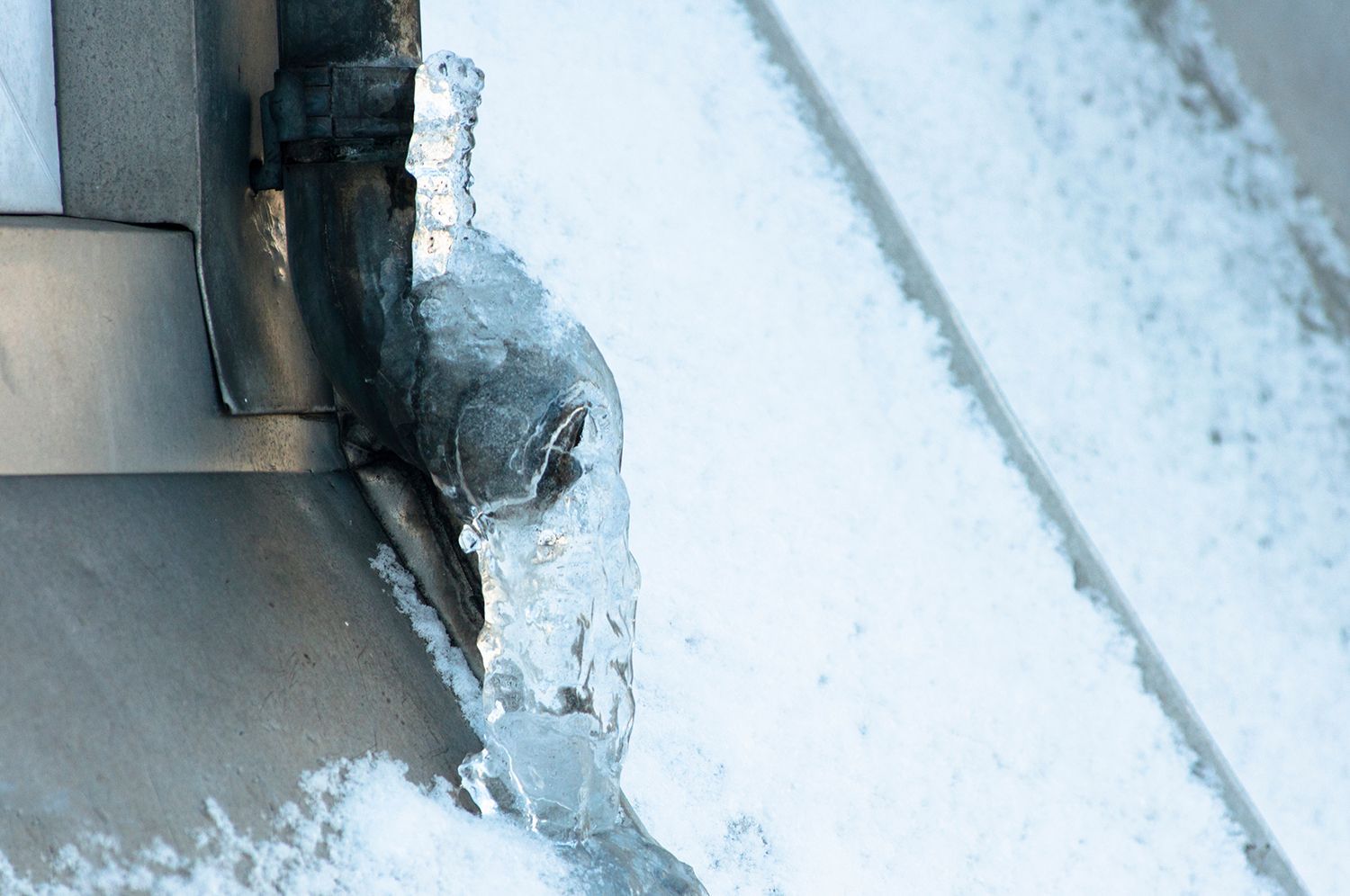Icy metal edge with snow buildup on a window or roof surface